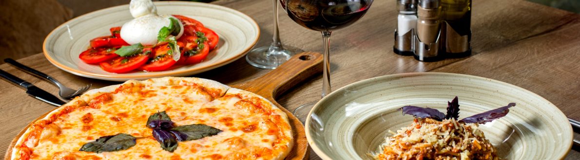 dinner set with margherita pizza salad pasta and wine